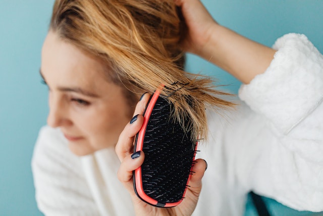 Femme qui utilise une brosse à cheveux pour les soins capillaires