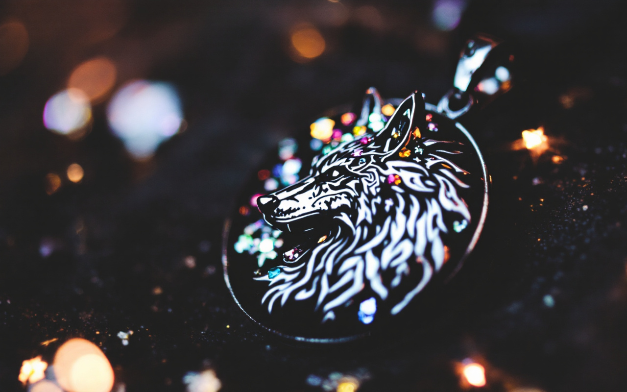 Gros plan d'un pendentif avec un motif de loup, montrant des détails en argent et des pierres précieuses scintillantes sur un fond sombre.